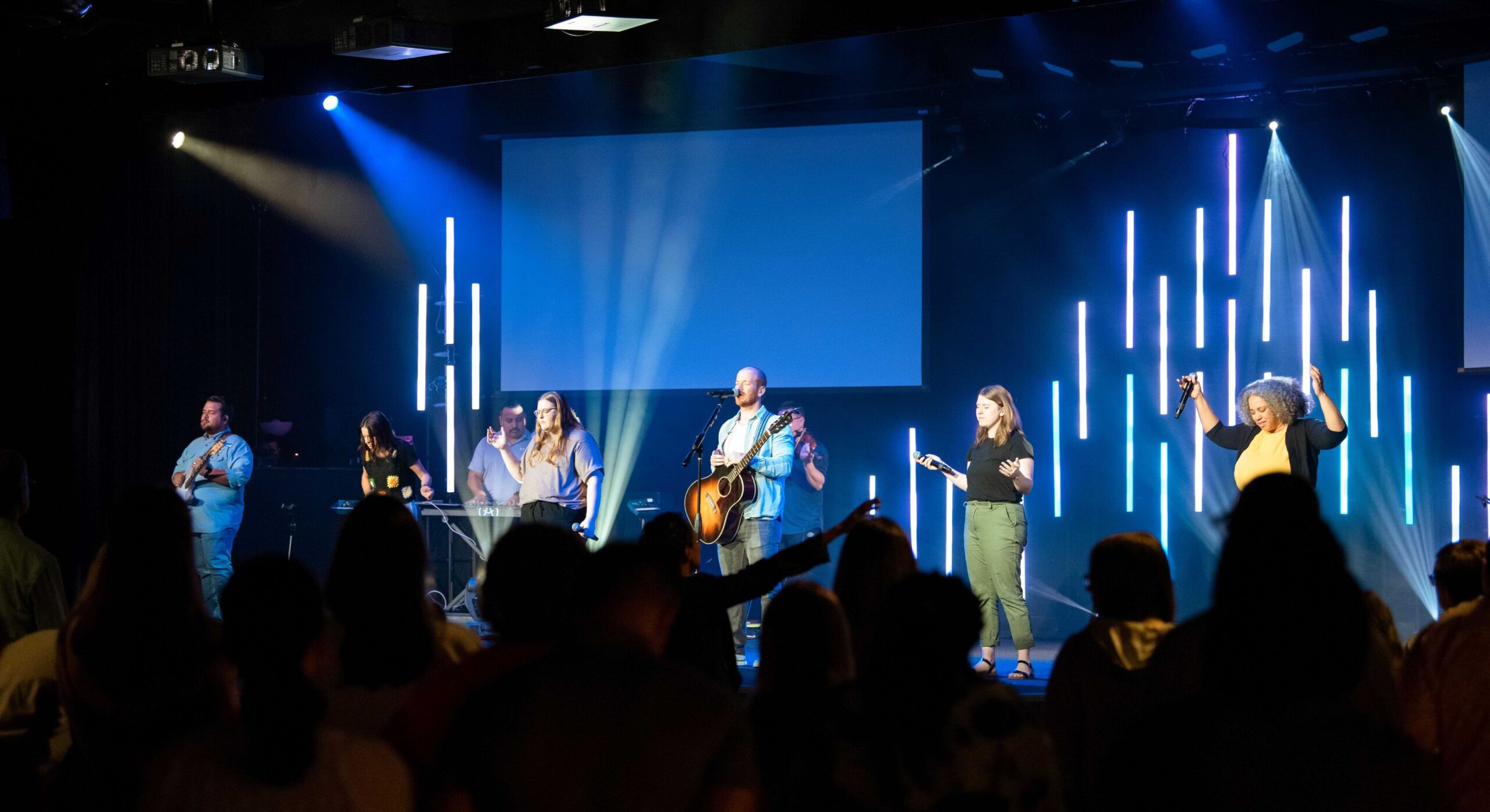 Large worship gathering with stage lit in warm red tones